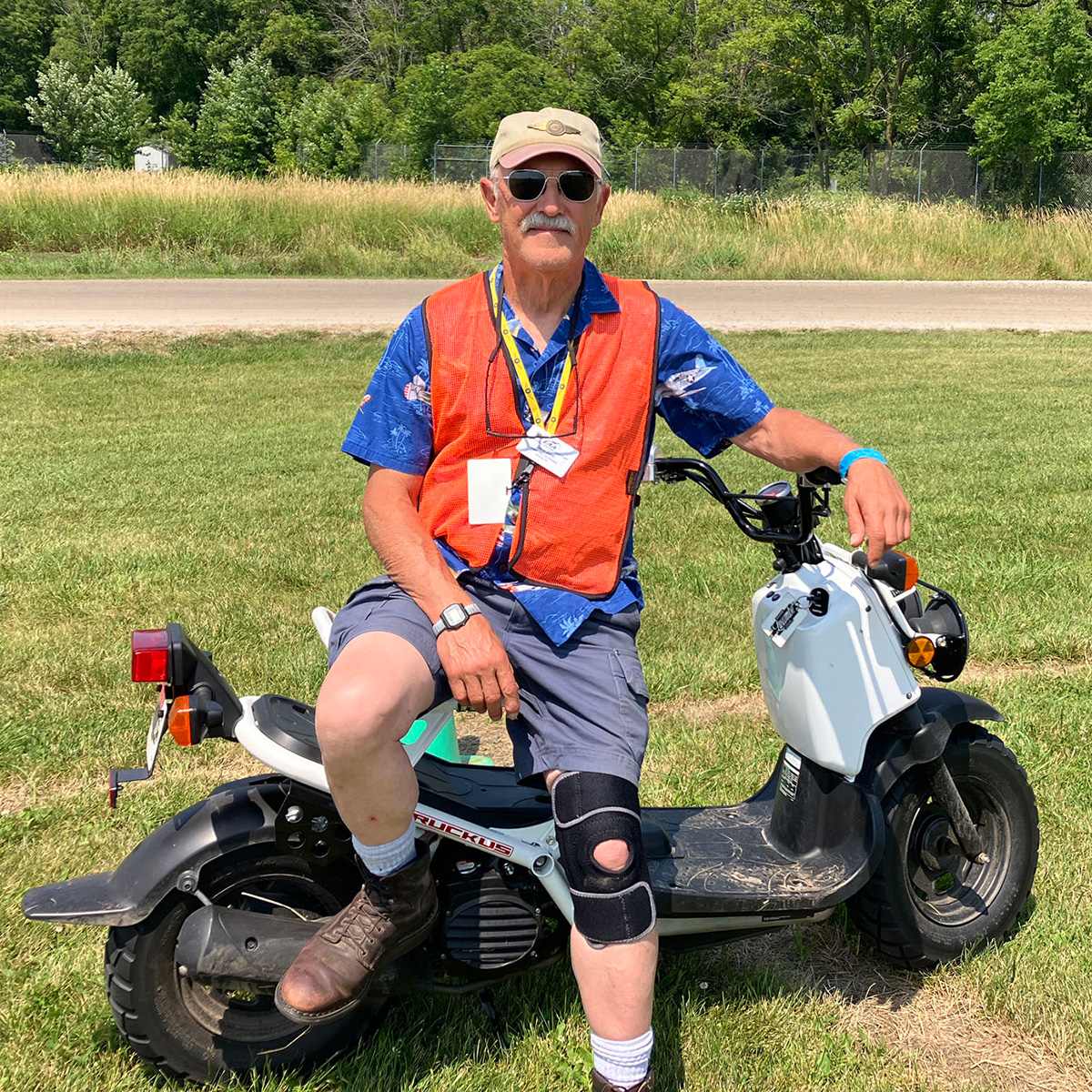 darrel sitting on a moped in his orange volunteer vest